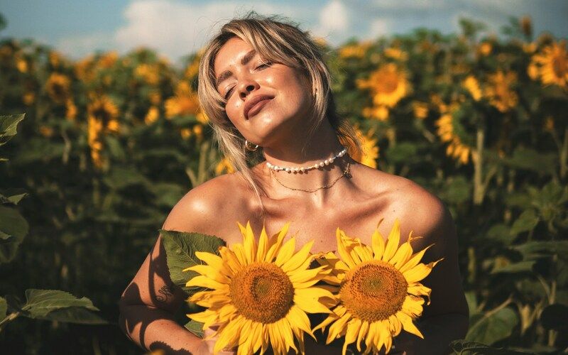 Frau mit blonden Haaren und zwei großen Sonnenblumen