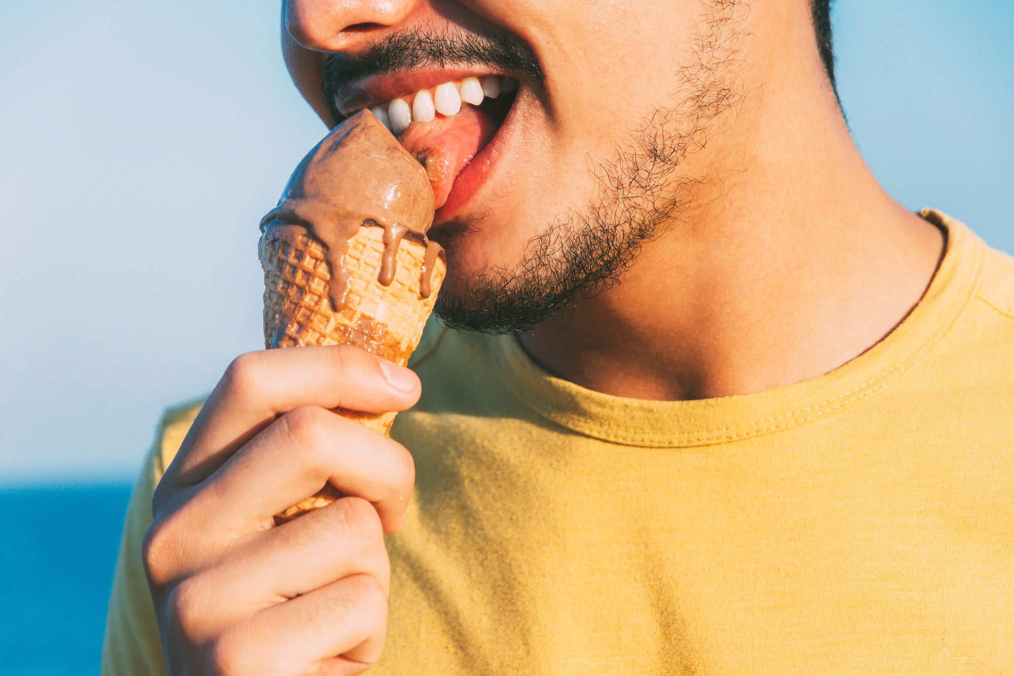 Mann leckt an einer Kugel Eis in der Waffel