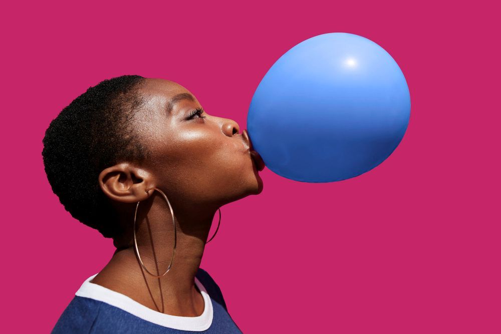 Eine Frau mit kurzen Haaren bläst einen blauen Ballon auf