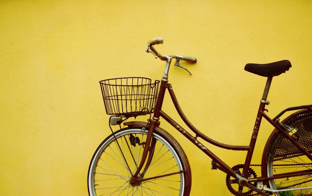 Ein braunes Fahrrad steht vor einer gelben Wand