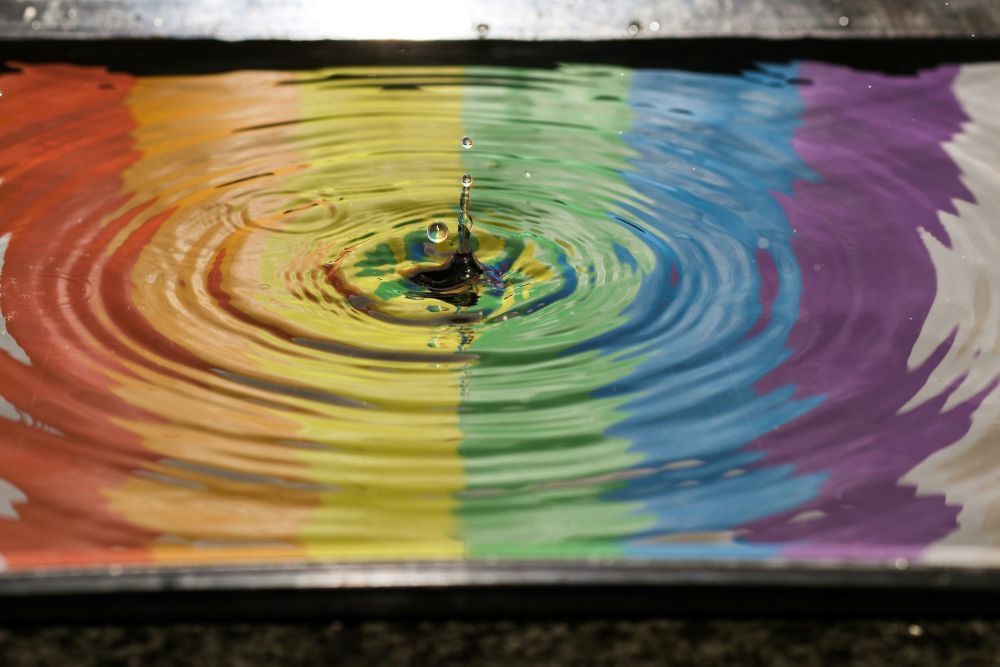 Eine Regenbogenflagge spiegelt sich im Wasser