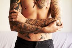 Mann mit gepiercten Nippeln und Tattoos