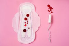 Periodenprodukte wie Binde und Tampon mit rotem Blut.