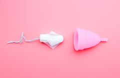 Ein Tampon und eine Menstruationstasse auf rosa Hintergrund