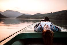 Eine Frau liegt auf einem kleinen Boot und blickt in den Himmel.