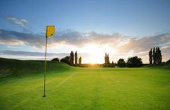 Ein Golfplatz, auf dem eine grüne Flagge steht, unter strahlend blauem Himmel