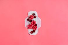 Auf einer Menstruationsbinde liegen rote Rosen