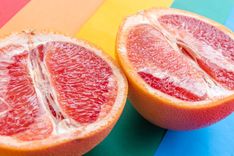 Eine aufgeschnittene Grapefruit liegt auf einem Regenbogen-Untergrund