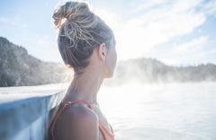 Eine Frau sitzt in einem Wasserbecken unter freiem Himmel