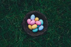 Ein Ostergeschenk, gefüllt mit bunten Eiern, liegt auf einer Wiese